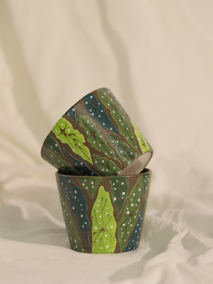 Two handcrafted forest leaf ceramic cups arranged on soft fabric.
