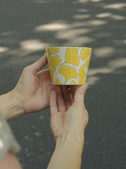 Hand holding a 270ml hand-painted ginkgo ceramic cup with carved yellow leaf outlines