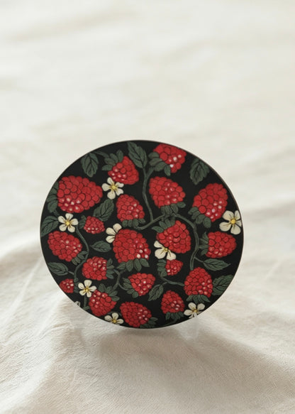 Round decorative item with red floral pattern on a white fabric background