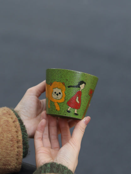 Hand-painted green ceramic cup featuring a girl and lion illustration