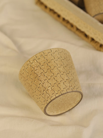 beige ceramic cup resting on soft fabric, showing its carved geometric texture.