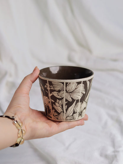 Hand holding a botanical sgraffito ceramic coffee cup