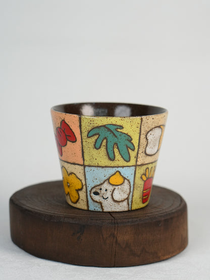 Front view of a garden patchwork ceramic cup displayed on a wooden stand.