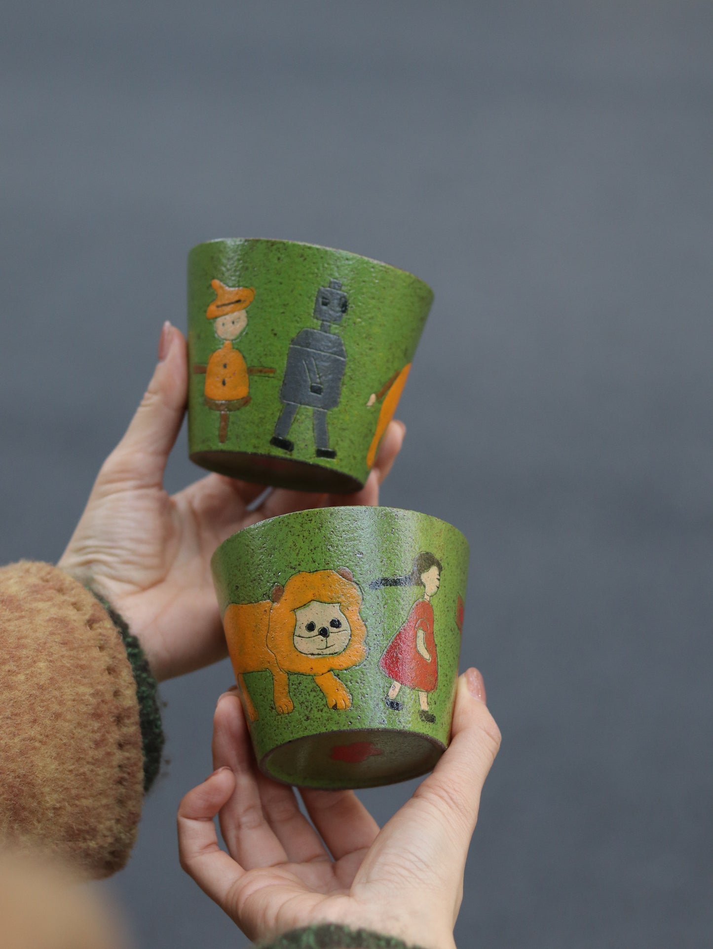 Two Emerald Journey hand-painted ceramic cups with carved storybook characters