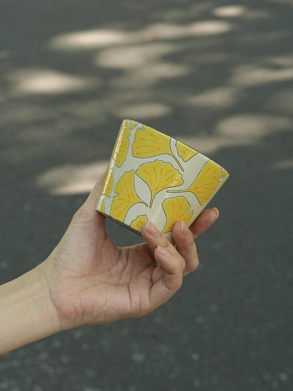 Hand holding a 270ml hand-painted ginkgo ceramic cup with carved yellow leaf outlines
