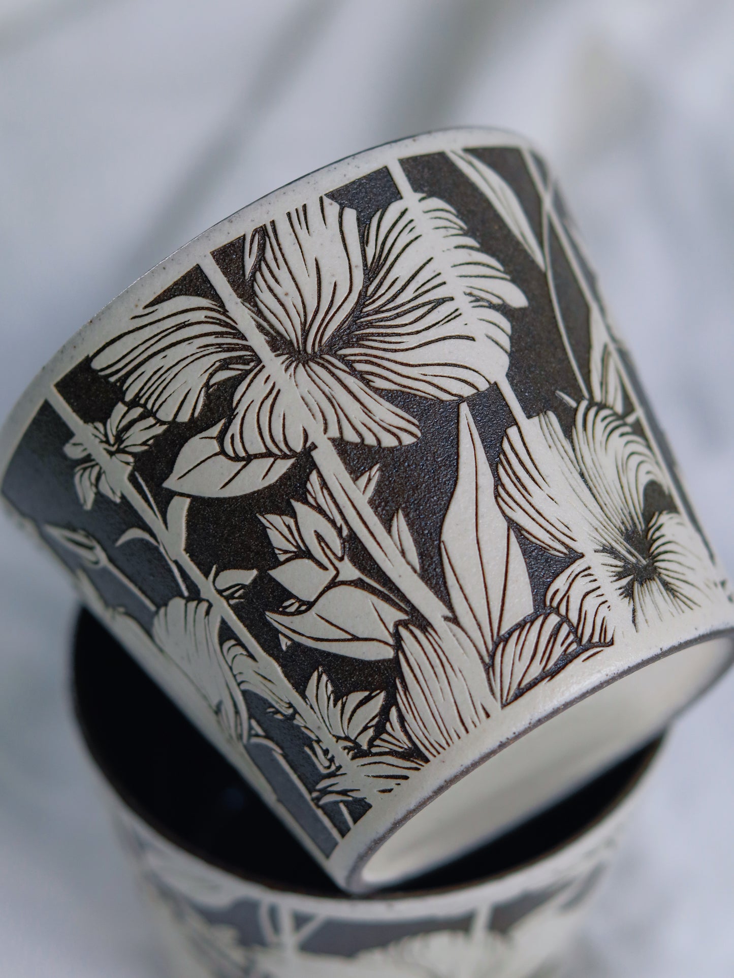 Close-up of hand-carved floral details on a sgraffito ceramic cup