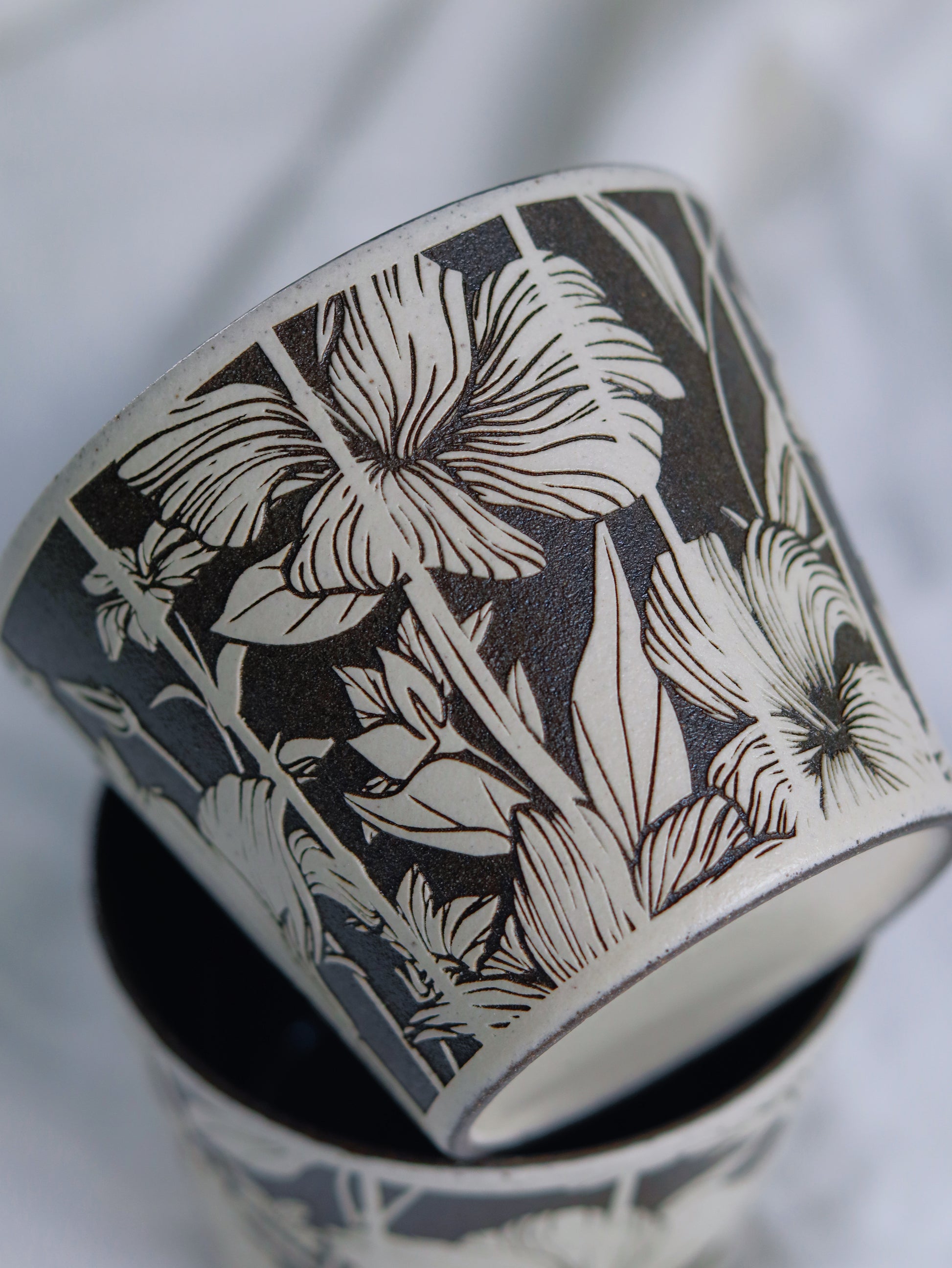 Close-up of hand-carved floral details on a sgraffito ceramic cup