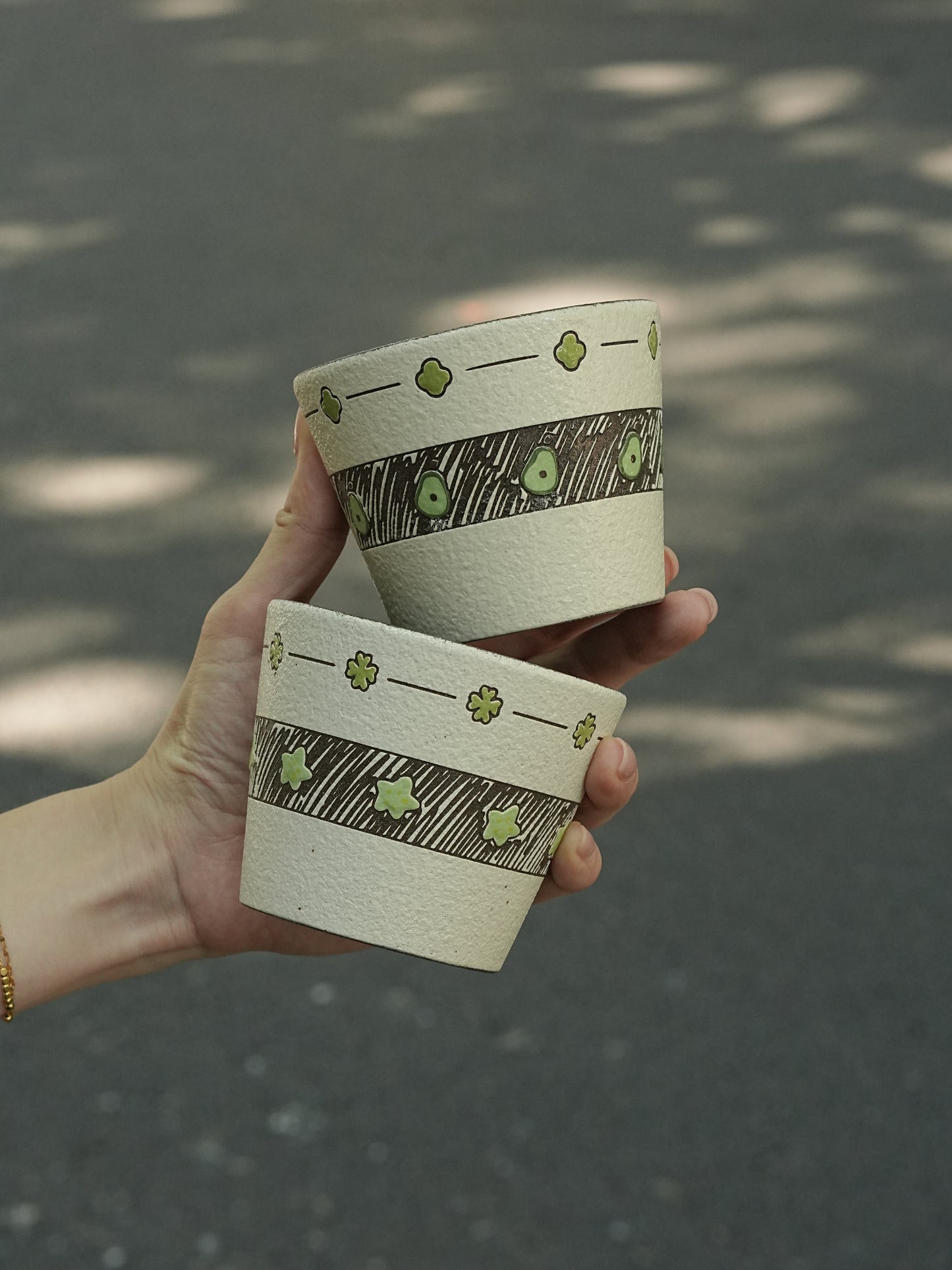 Two hand-painted green ceramic cups with avocado and star designs
