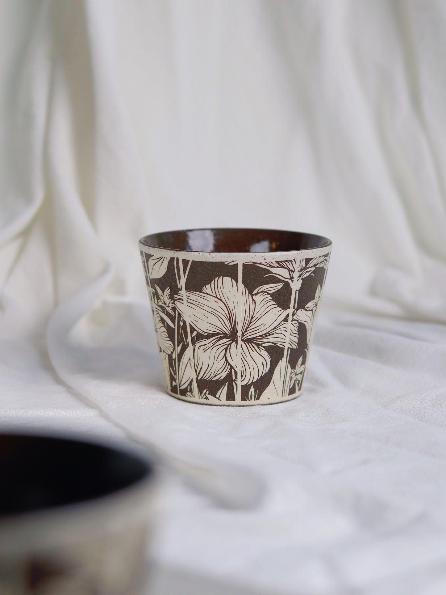Single 270ml botanical sgraffito ceramic cup on white fabric
