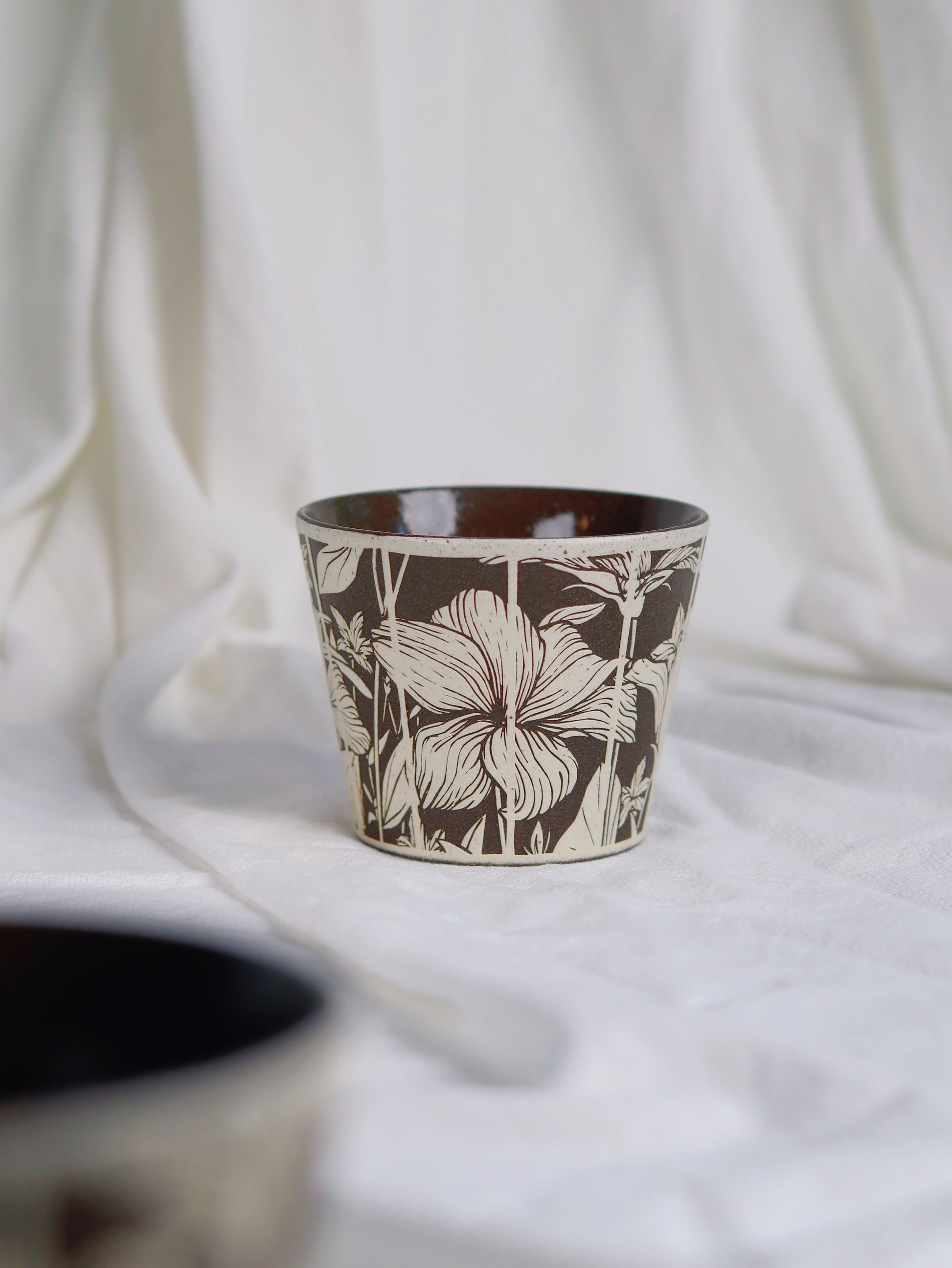Single 270ml botanical sgraffito ceramic cup on white fabric