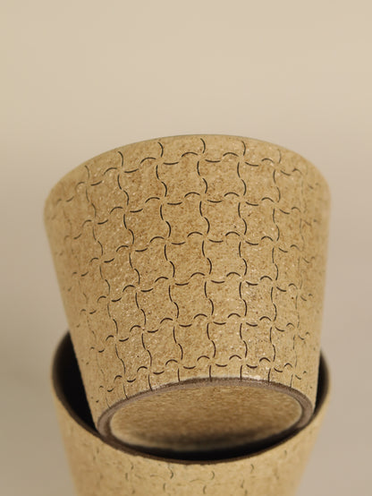Close-up of a geometric ceramic cup showing its hand-carved pattern and base.