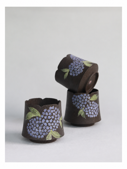 Three handcrafted hydrangea zisha clay cups displayed together on a neutral background.