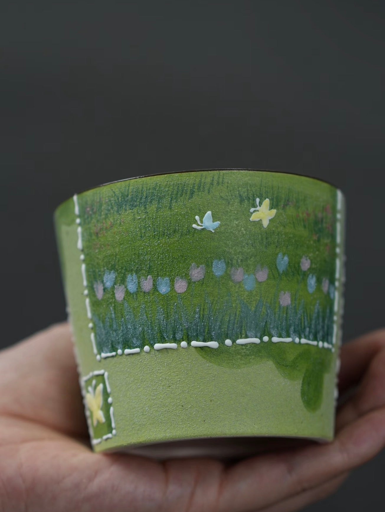 Close-up of white cat chasing butterflies on a green ceramic cup