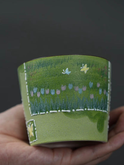 Close-up of white cat chasing butterflies on a green ceramic cup