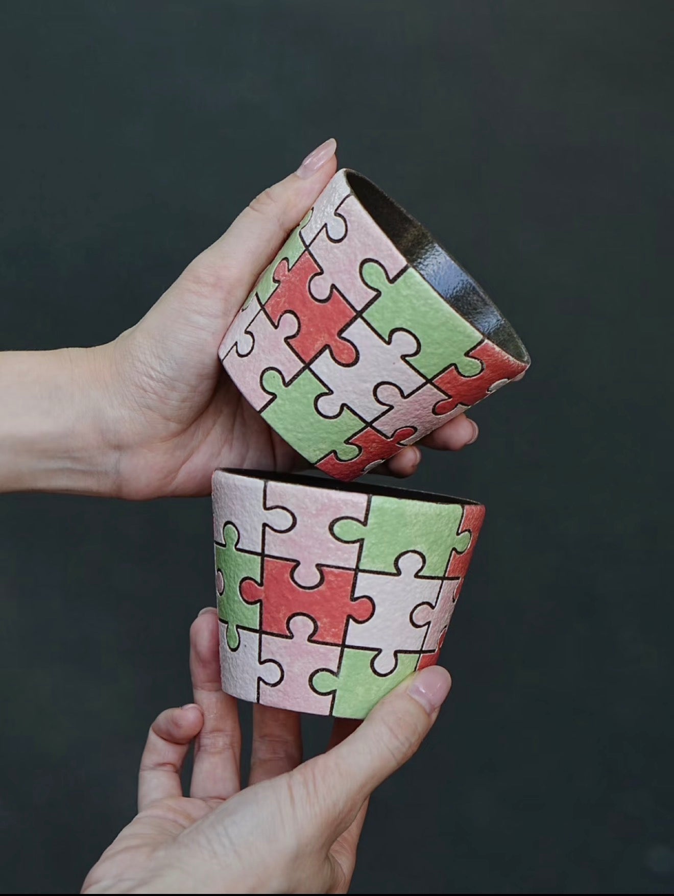 Close-up of a hand-painted puzzle ceramic cup with carved outlines in pink, green and ivory