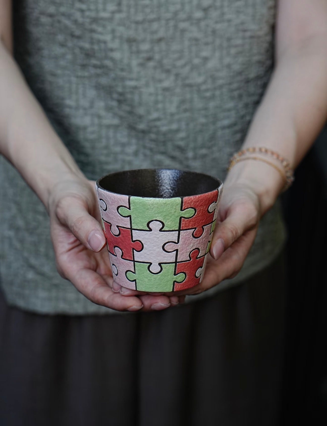 Close-up of a hand-painted puzzle ceramic cup with carved outlines in pink, green and ivory