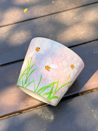 pink ceramic cup with hand-painted white daisies and green leaves