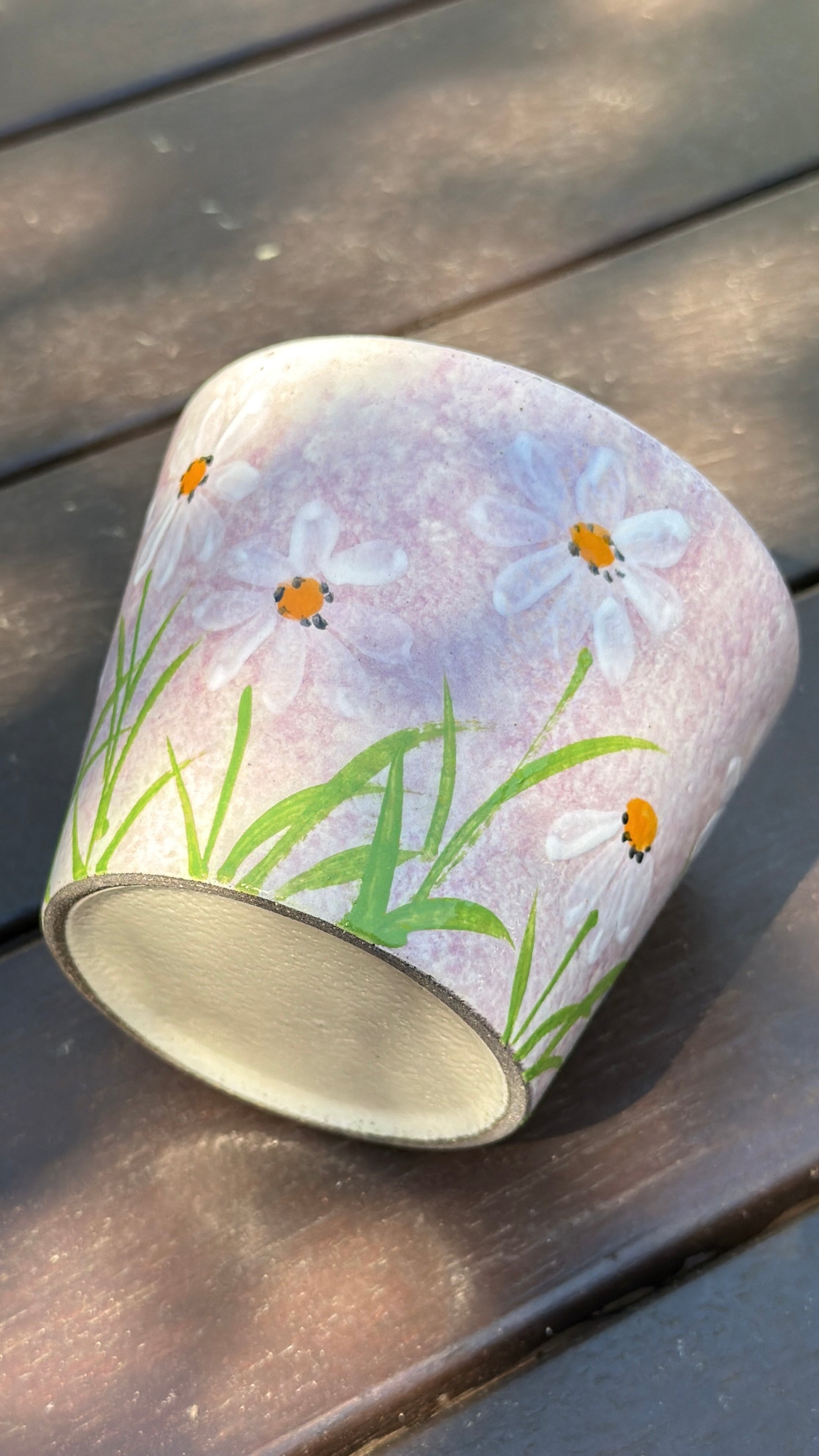 pink ceramic cup with hand-painted white daisies and green leaves