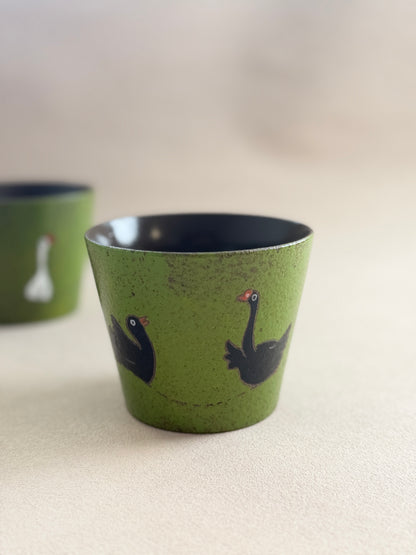 Black goose ceramic cup displayed beside a matching green cup.