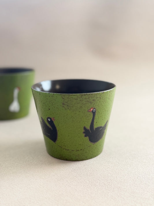 Black goose ceramic cup displayed beside a matching green cup.