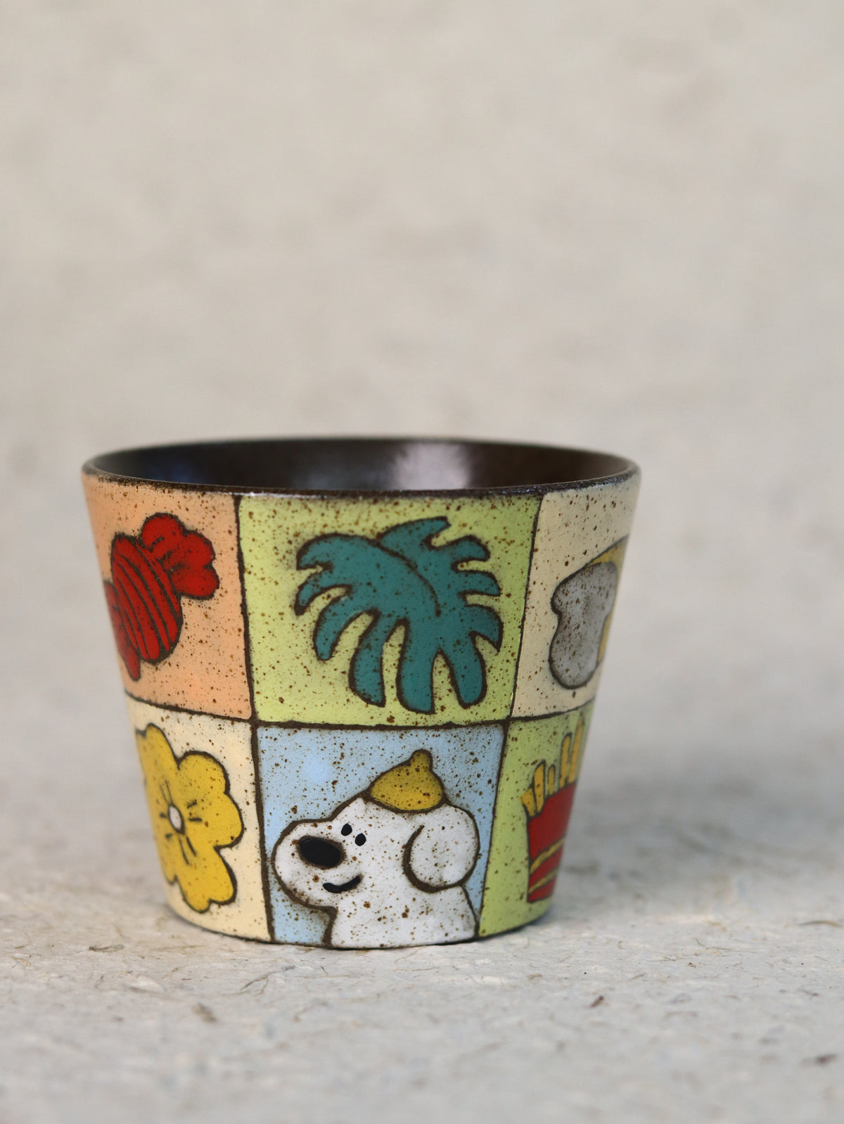 Hand-painted garden patchwork ceramic cup featuring colourful fruit, flowers, leaves and a playful dog.