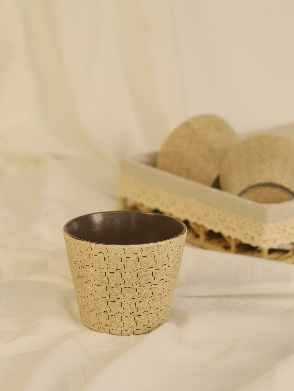 Hand-carved geometric ceramic cup with a warm beige textured finish and dark glazed interior.
