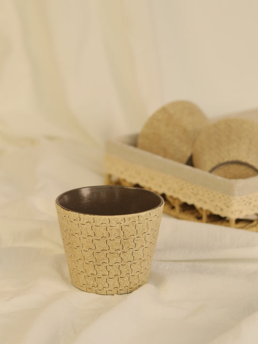 Hand-carved geometric ceramic cup with a warm beige textured finish and dark glazed interior.