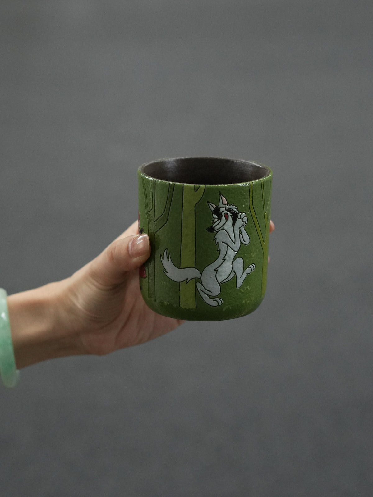 Hand-painted ceramic cup showing the Big Bad Wolf walking through a green forest.