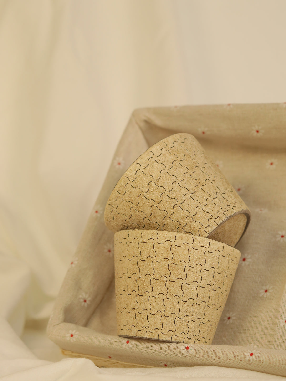 Handcrafted beige ceramic cups displayed together in a decorative tray.