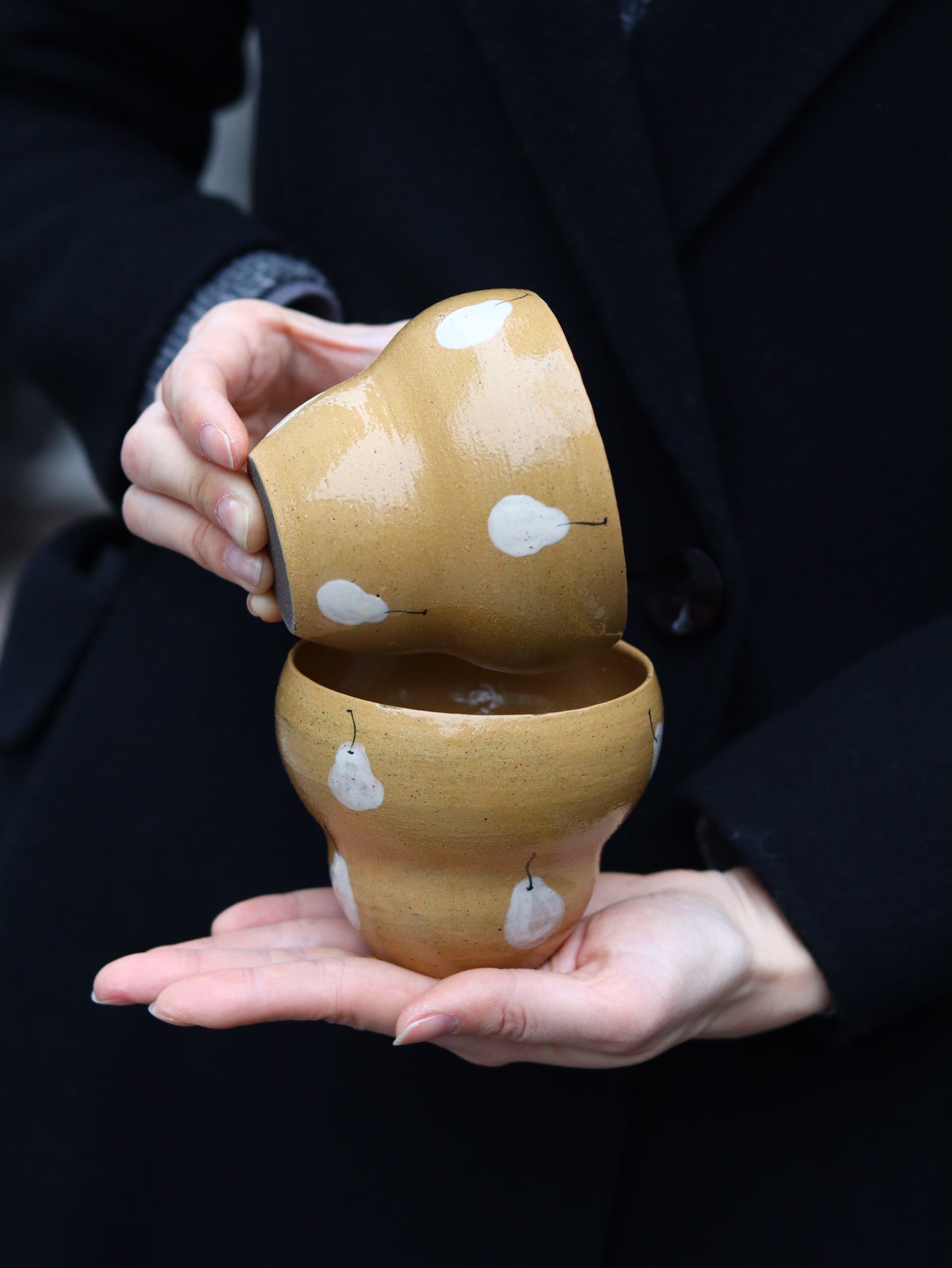 Person holding a pair of wooden shoes with white patterns on a dark background