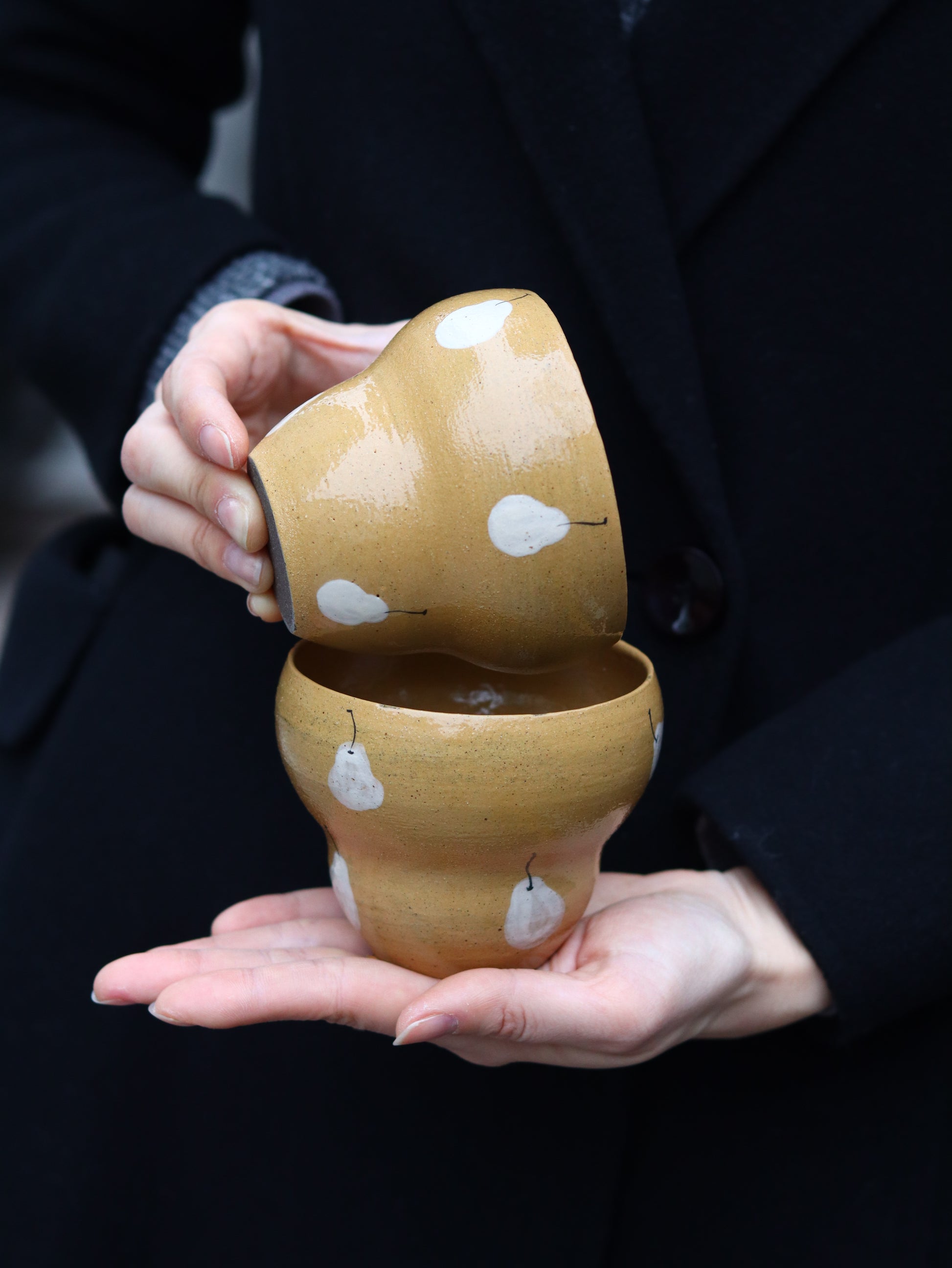 Person holding a pair of wooden shoes with white patterns on a dark background