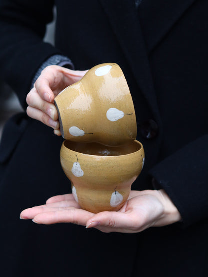 Person holding a pair of wooden shoes with white patterns on a dark background