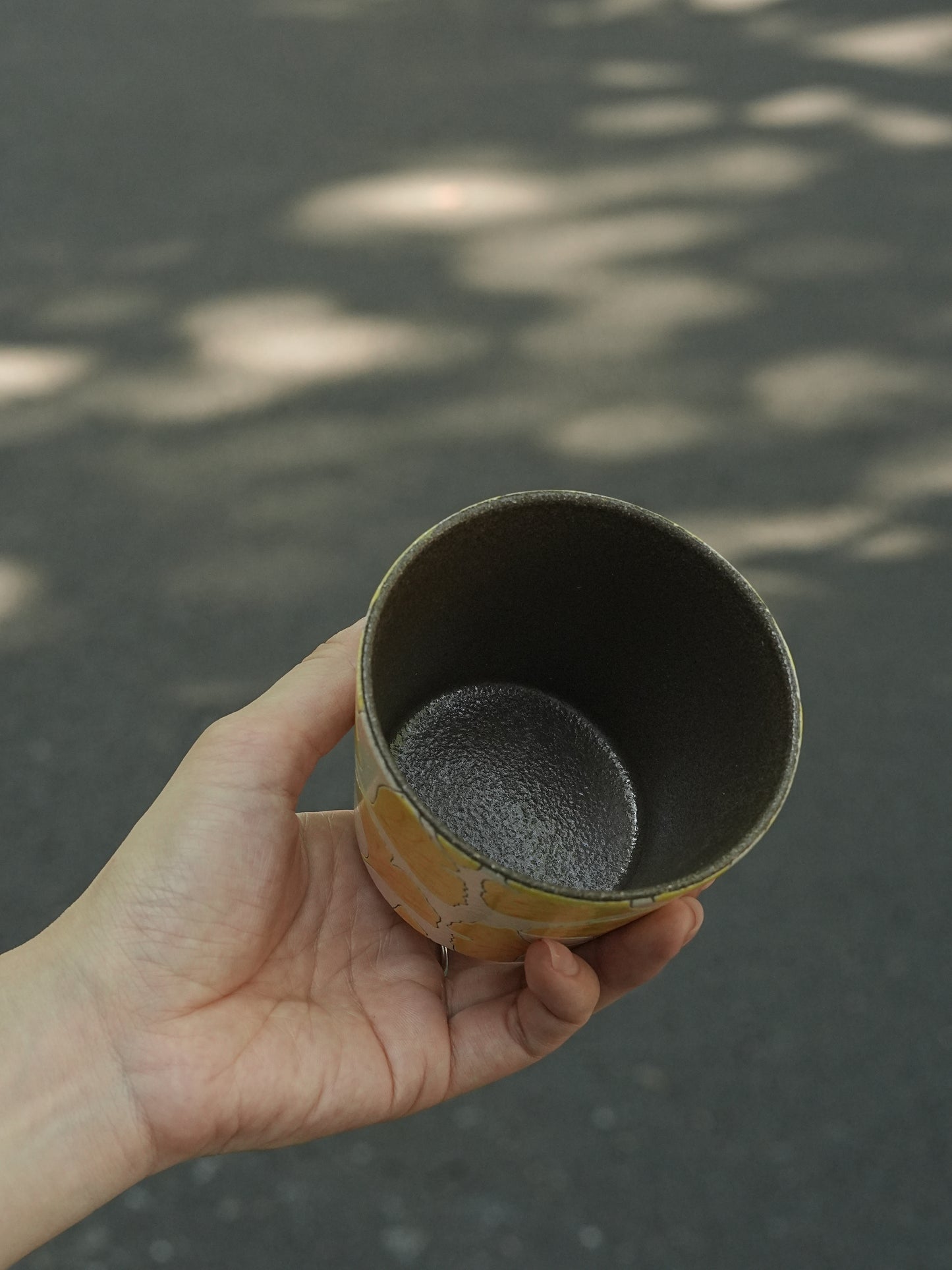 Hand holding a 270ml hand-painted ginkgo ceramic cup with carved yellow leaf outlines