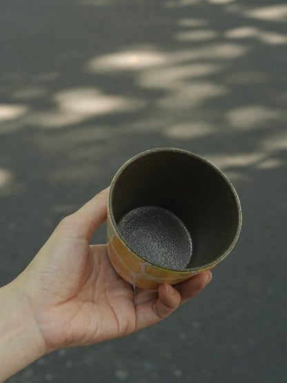 Hand holding a 270ml hand-painted ginkgo ceramic cup with carved yellow leaf outlines