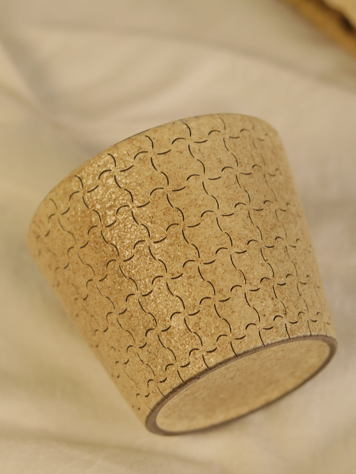 Close-up of a ceramic cup showing the repeating hand-carved line pattern.