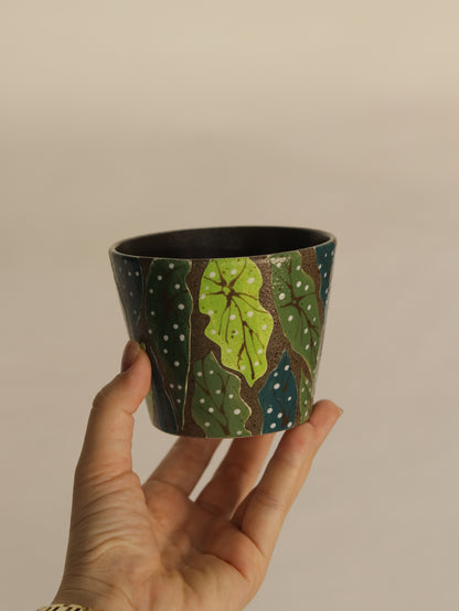 Hand holding a 270ml forest leaf pottery clay cup with a textured dark green finish.
