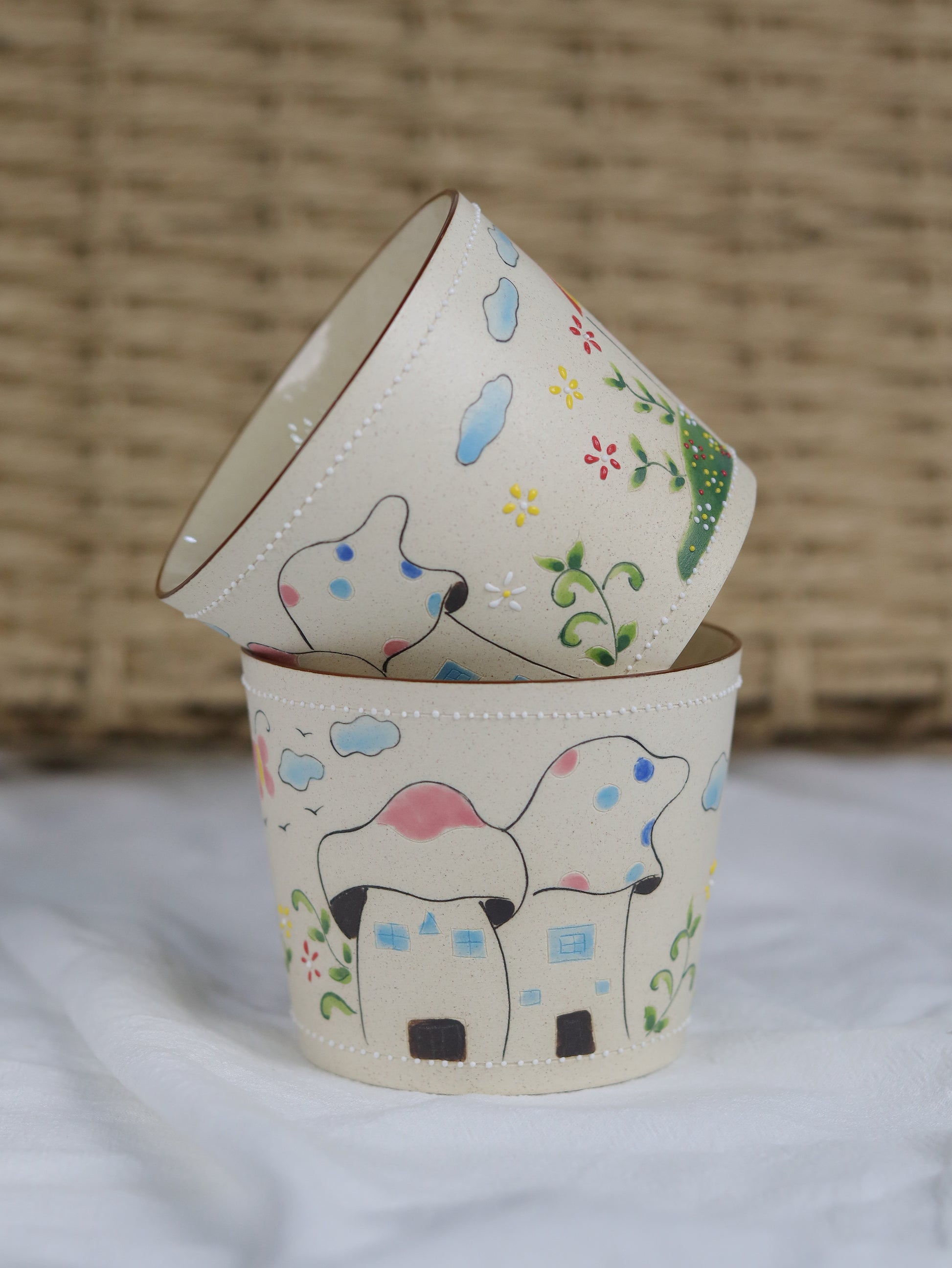 Two small ceramic pots with hand-painted designs of dogs and flowers on a textured surface.