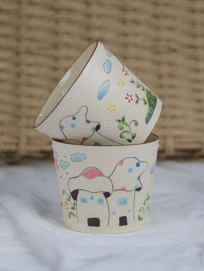 Two small ceramic pots with hand-painted designs of dogs and flowers on a textured surface.
