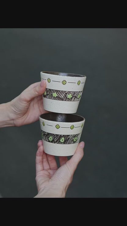 Two hand-painted green ceramic cups with avocado and star designs