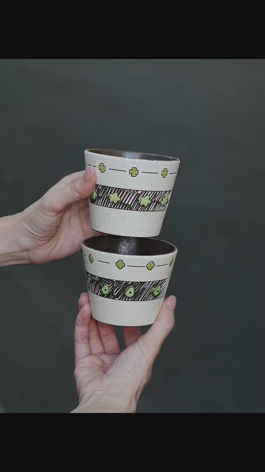 Two hand-painted green ceramic cups with avocado and star designs